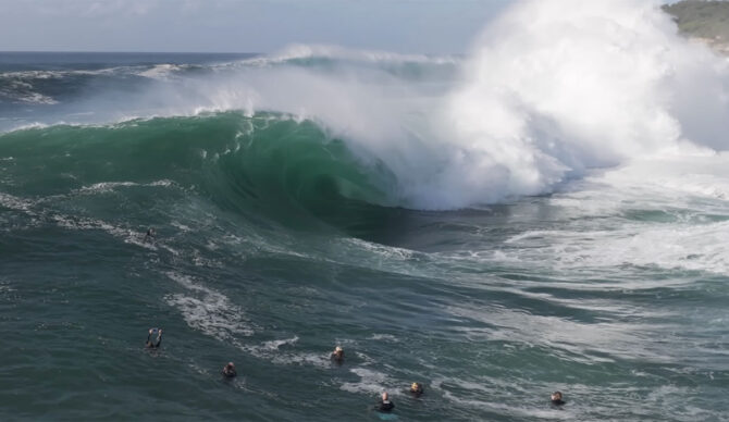 Cape Solander wave with surfers in front of it